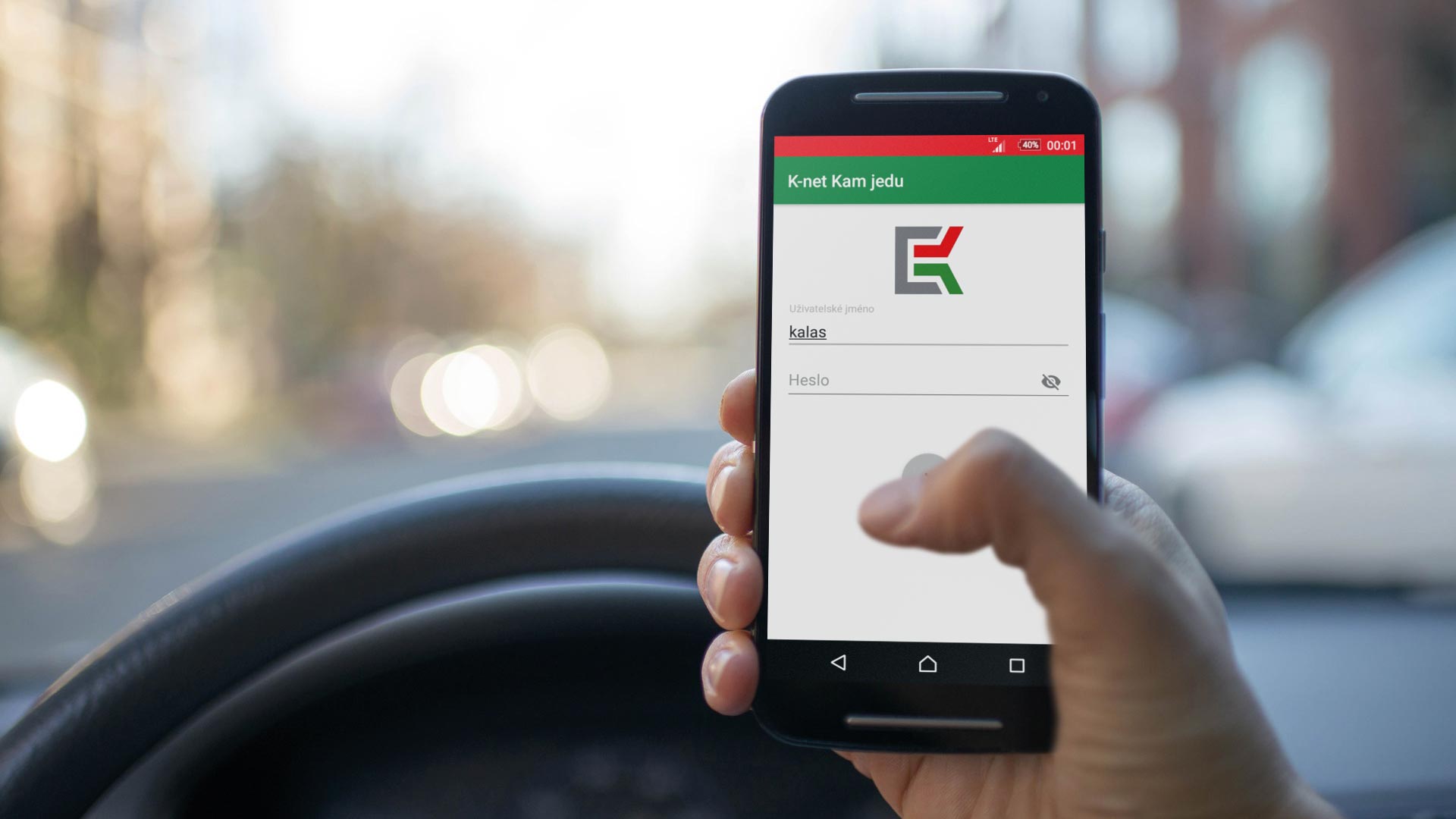 Pohled na smartphon a přihlašovací stránku aplikace Kam Jedu v autě